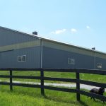 Large blue and gray horse barn building situated on farm property