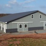 Horse shelter project with gray and green siding and a dark roof