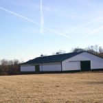 Large horse barn project with white siding and black roof